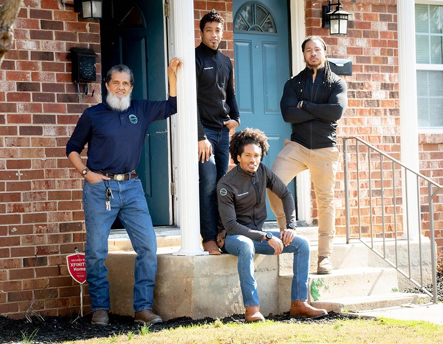 Four employees of Saboor Construction pose on steps of a building